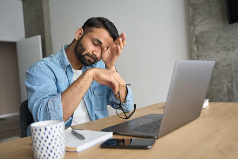A man suffering from burnout while sitting in front of his laptop